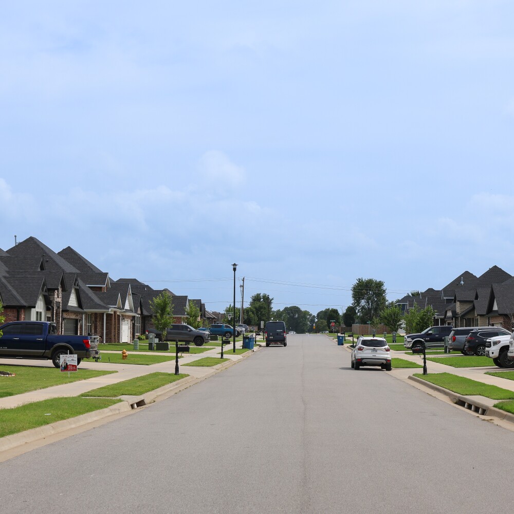Vehicles are parked in driveways and on the street in a new residential neighborhood