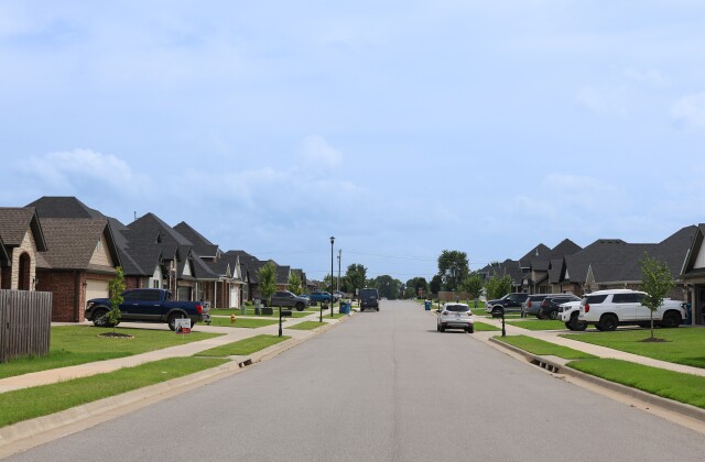 Vehicles are parked in driveways and on the street in a new residential neighborhood