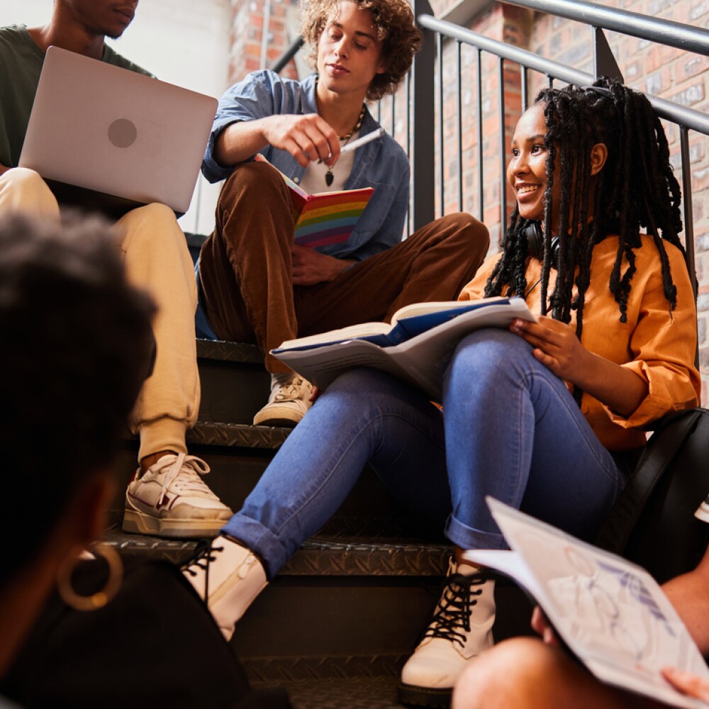 Smiling college students talking together on steps between classes