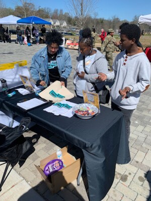 A group of youth gather at a display table featuring educational materials.