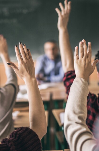 Students raise hands in classroom