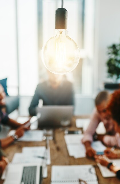 Light bulb in foreground business meeting of entrepreneurs