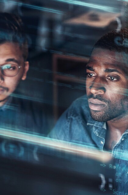 Two computer programmer work in an office superimposed over multiple lines of code.