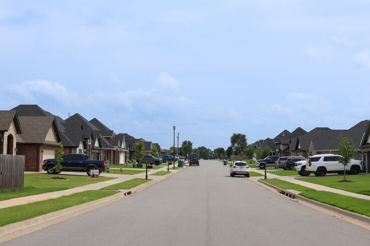 Vehicles are parked in driveways and on the street in a new residential neighborhood