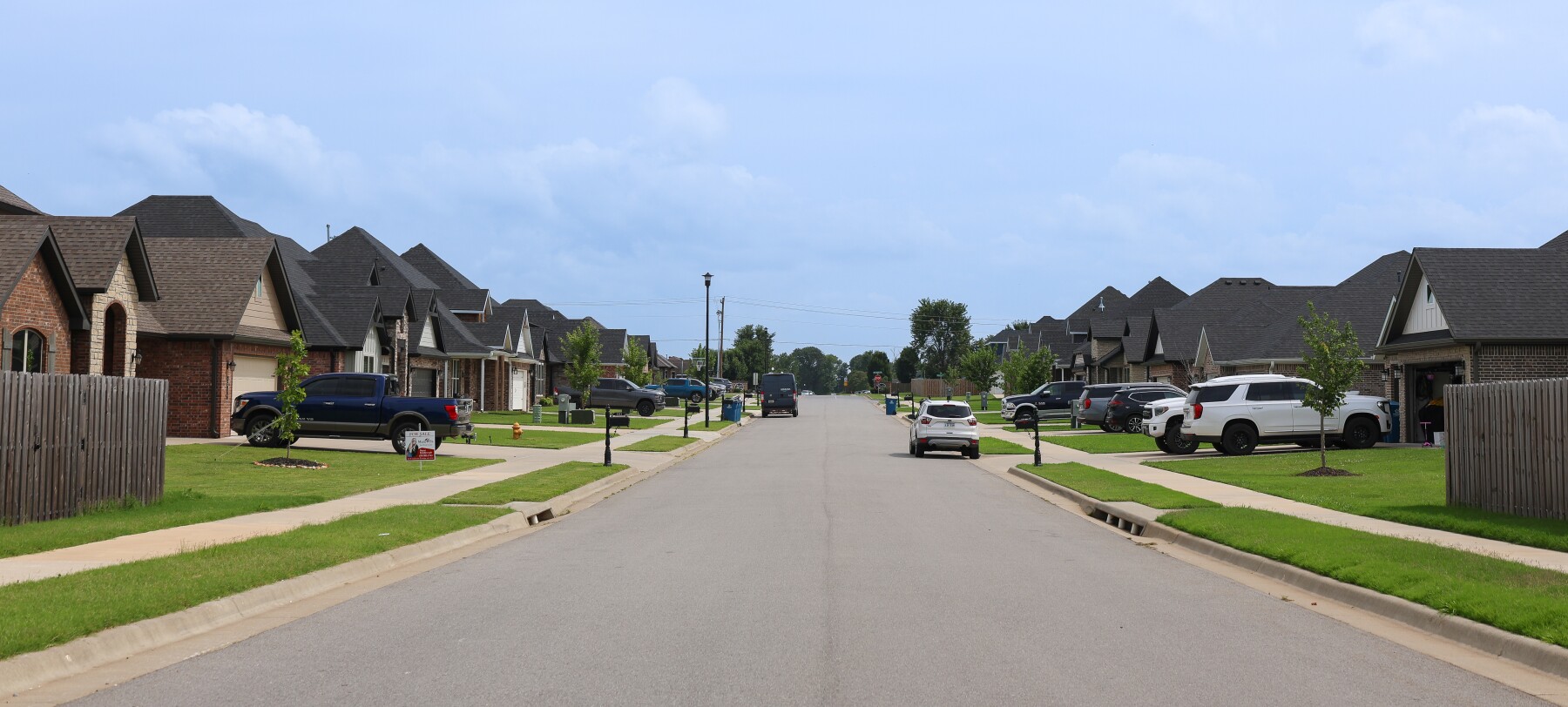 Vehicles are parked in driveways and on the street in a new residential neighborhood