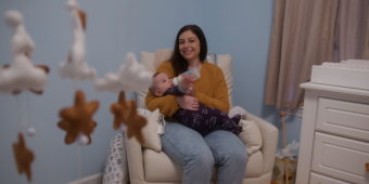 A women cradles her baby in a rocking chair. 