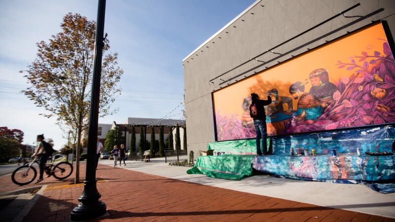 Artist painting a mural in Bentonville