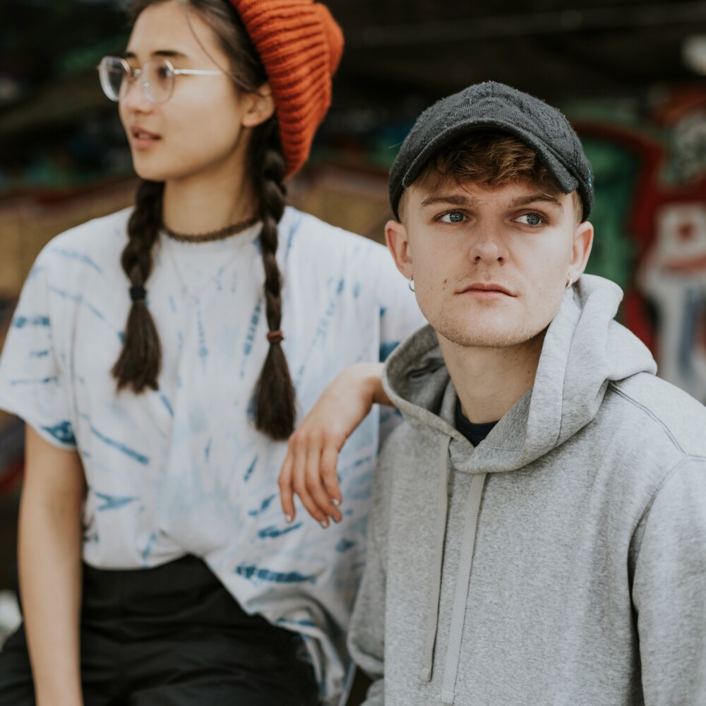A male and female student sit next to each other in casual outfits. 