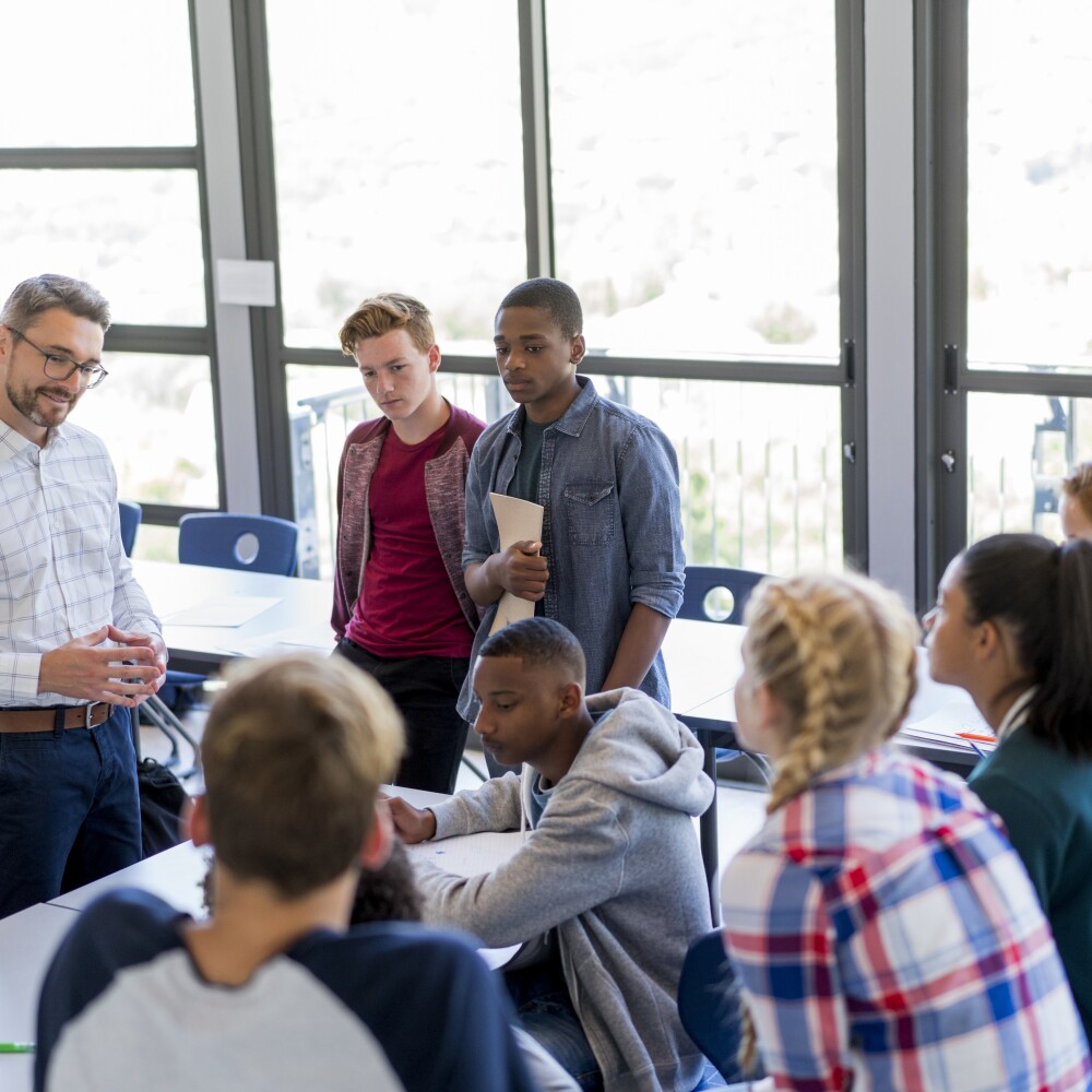 Multi-ethnic students discussing with teacher