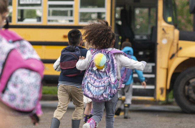 Diverse group of happy students running to school bus
