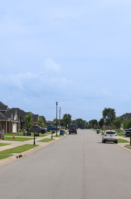 Vehicles are parked in driveways and on the street in a new residential neighborhood