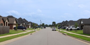 Vehicles are parked in driveways and on the street in a new residential neighborhood