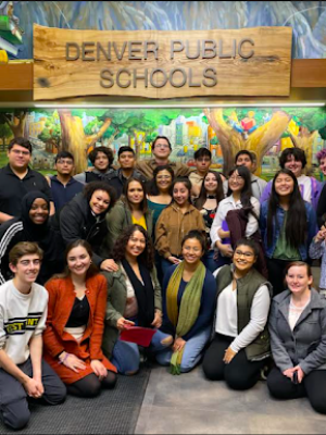 Students pose for a group photo in front of a Denver Public Schools sign. 