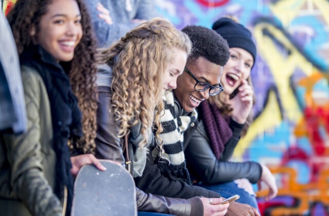 A group of young adults laugh and smile at an outdoor event. 
