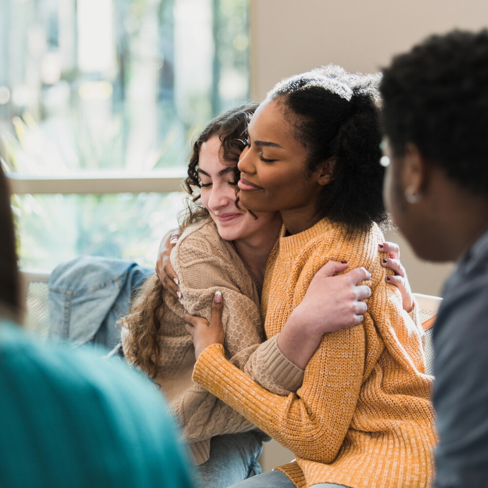 Two young adults embrace in support of each other. 