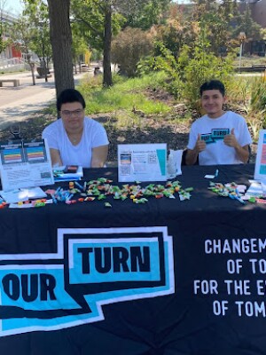 Two students sit at an informational table. 