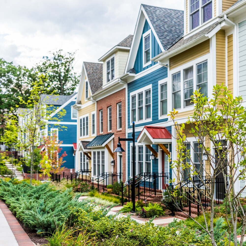 Row of colorful, residential townhouses, homes, houses with brick patio gardens in summer