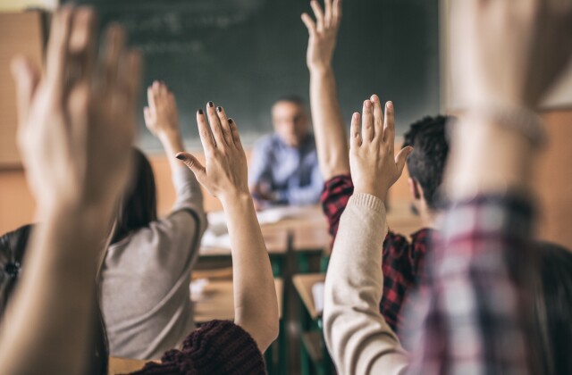 Students raise hands in classroom