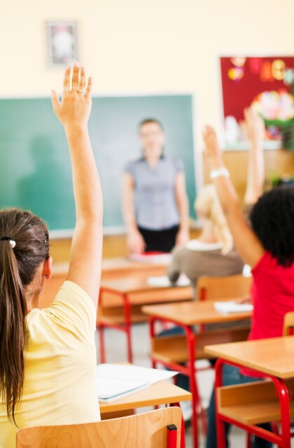 High School Students raise their hands in class. 