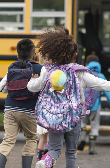 Diverse group of happy students running to school bus