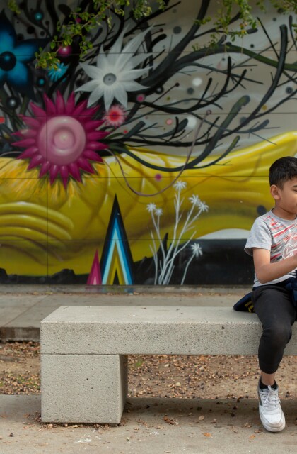Elementary boy and girl reading in front of mural
