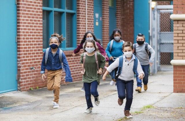 Students with face masks running outside school building