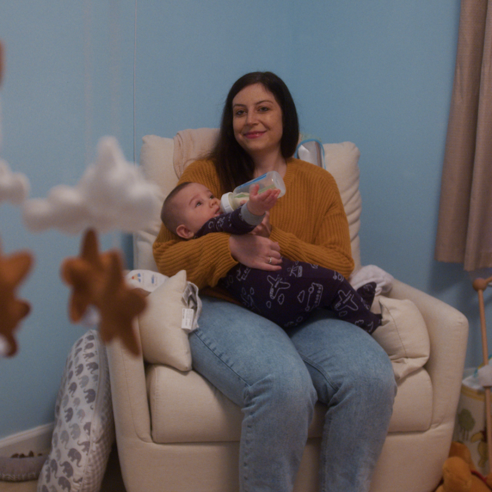 A women cradles her baby in a rocking chair. 