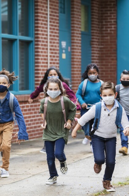 Students with face masks running outside school building