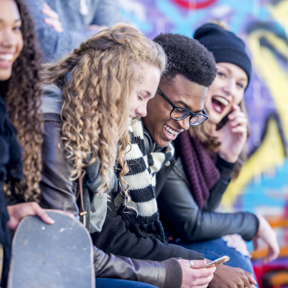 A group of young adults laugh and smile at an outdoor event. 