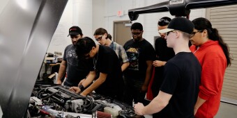A group of young people work on fixing a car  engine.