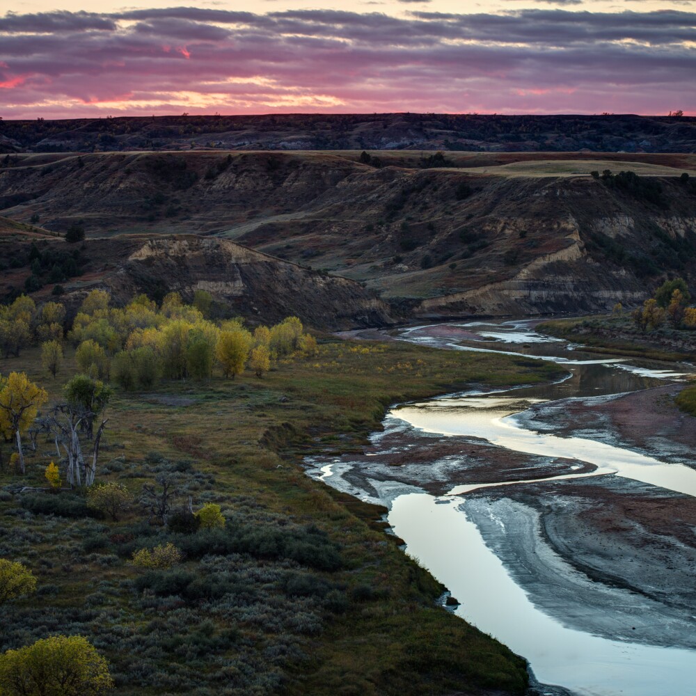 An aerial view of Theodore Roosevelt National Park shows a river, canyons and meadows. 