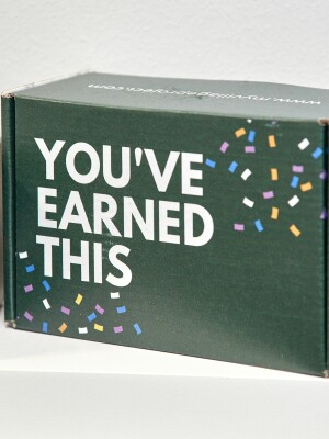 A promotional gift box is printed with You've Earned This
