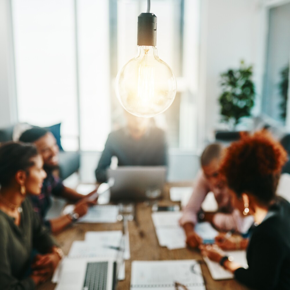 Light bulb in foreground business meeting of entrepreneurs