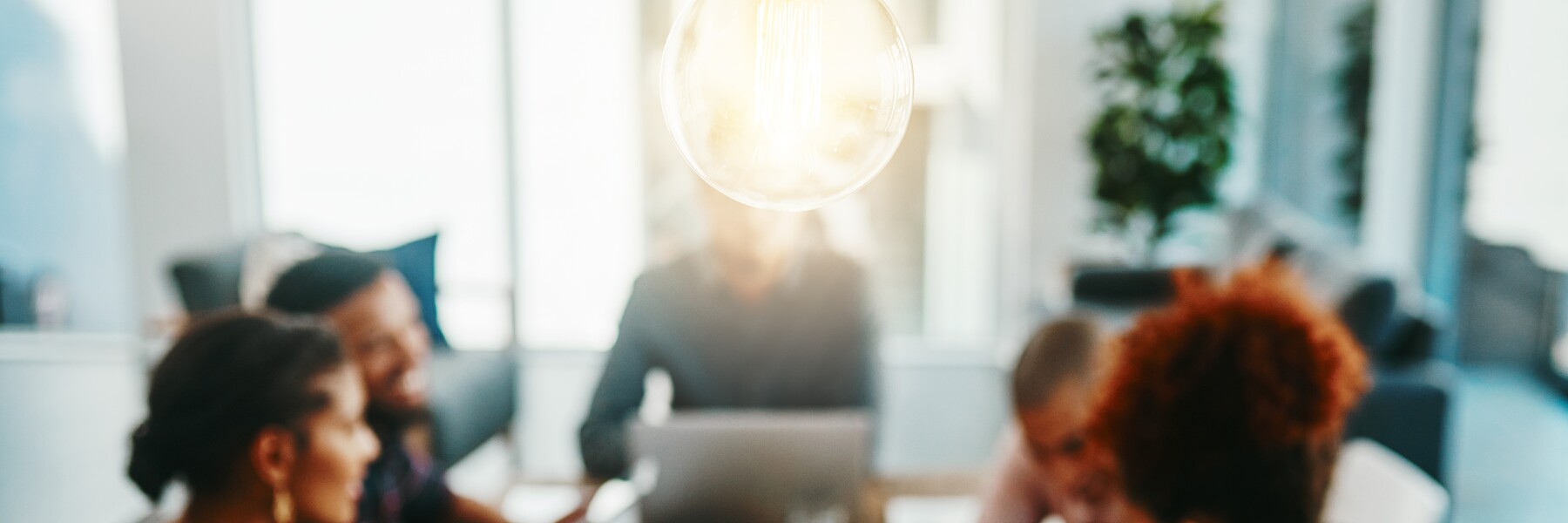 Light bulb in foreground business meeting of entrepreneurs